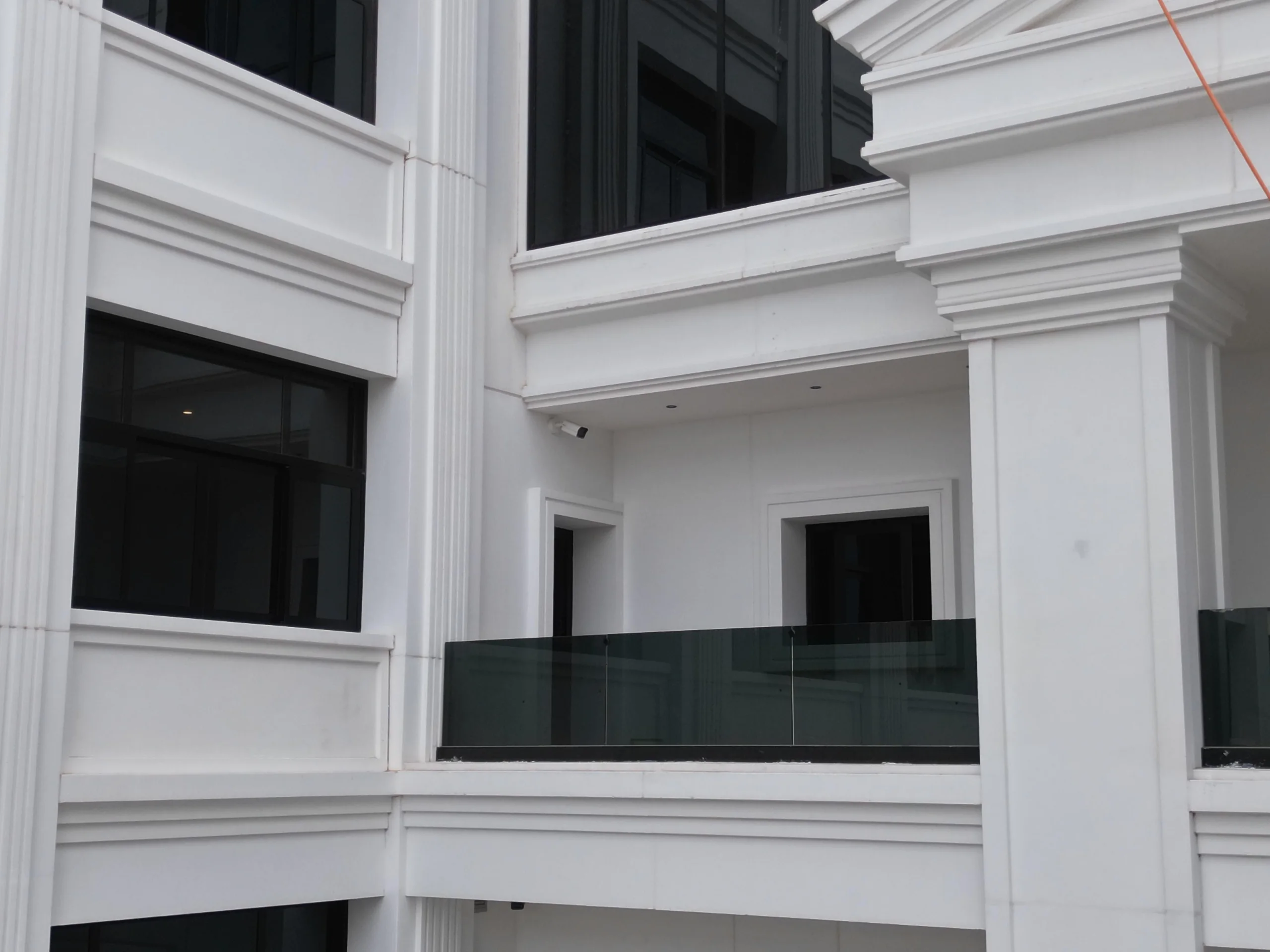 Entrance terrace glass balustrade assembly and classical column capital detailing
