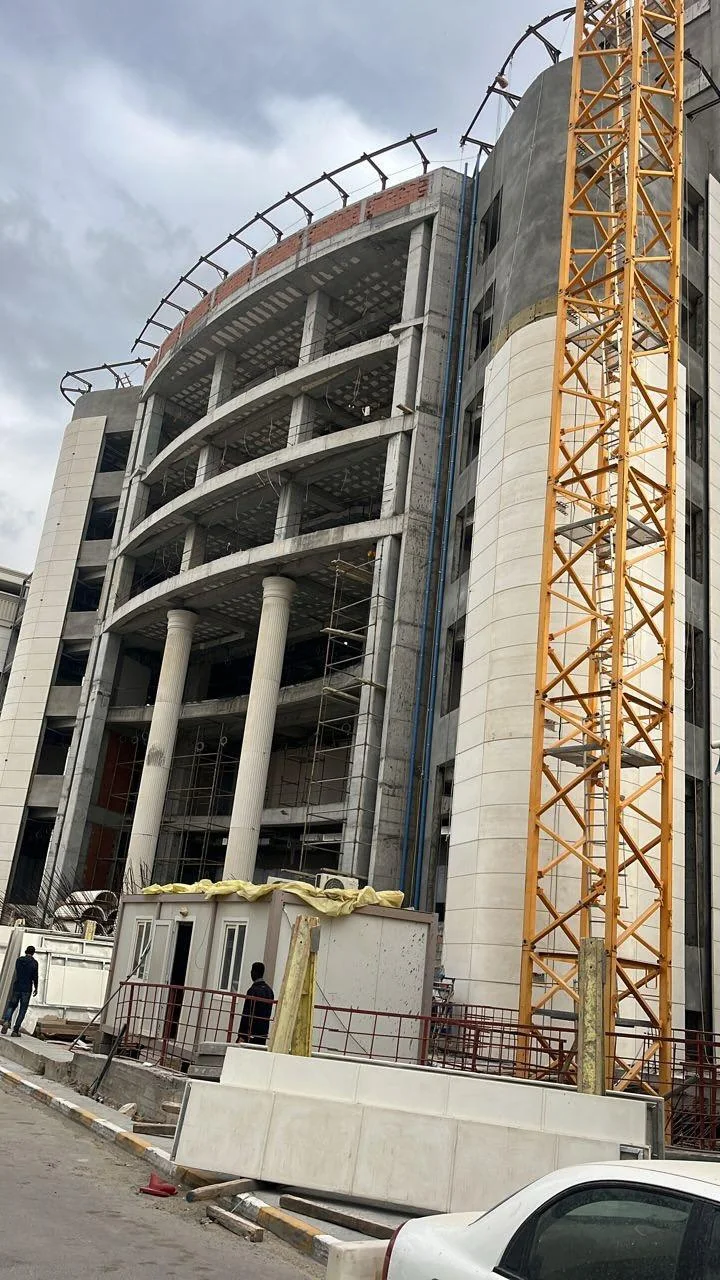 Construction milestone: Structural concrete frame, curved roof steel, and tower crane